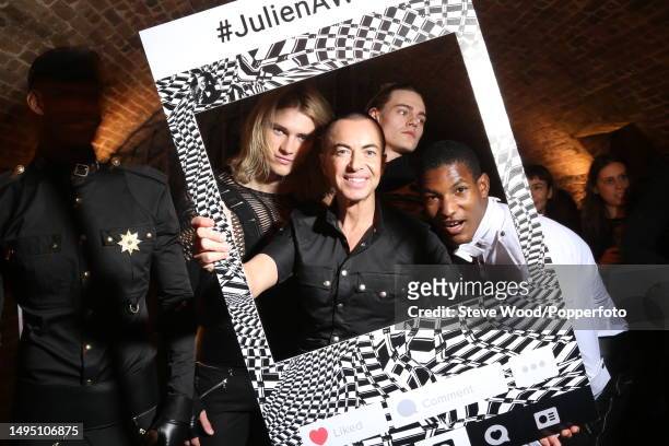 Backstage at the Julien Macdonald show during London Fashion Week Autumn/Winter 2016/17, the designer poses with a selfie frame with two models...