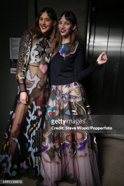 Backstage at the Mary Katrantzou show during London Fashion Week Autumn/Winter 2016/17, two model wear black tulle maxi dresses with pleated skirts,...