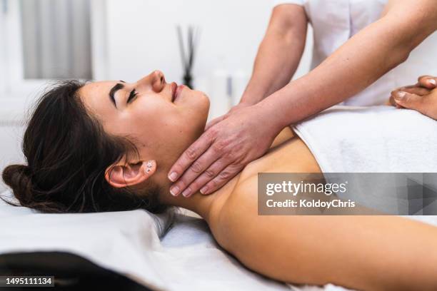 therapeutic neck lymphatic drainage: woman receiving treatment on clinic bed, hands of female physiotherapist visible - sistema linfatico foto e immagini stock