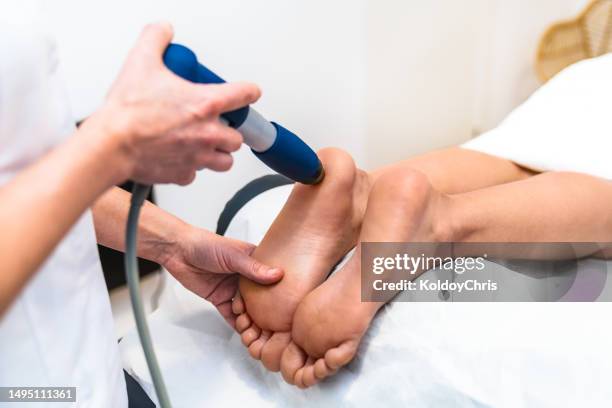 accelerated recovery: shockwave therapy for foot pain, expert fisiotherapist treating patient on treatment bed - shockwave therapy stock pictures, royalty-free photos & images