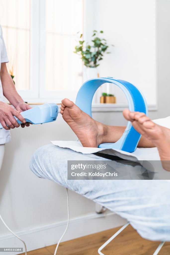 Magnetotherapy Treatment: Fisioterapist using control device for relaxing muscles, promoting bone tissue, vasodilation, and pain relief.