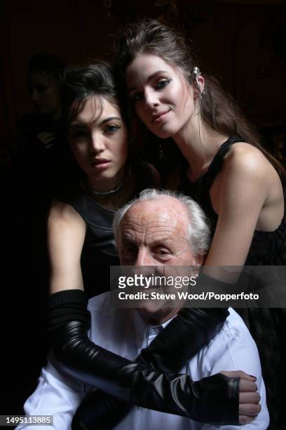 Backstage at the Paul Costelloe show during London Fashion Week Autumn/Winter 2016/17, the designer poses with two models, both wearing long leather...