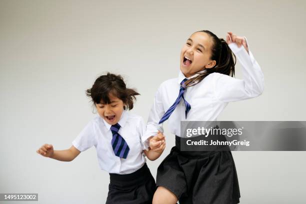 playful sisters holding hands and jumping - striped shirt stock pictures, royalty-free photos & images