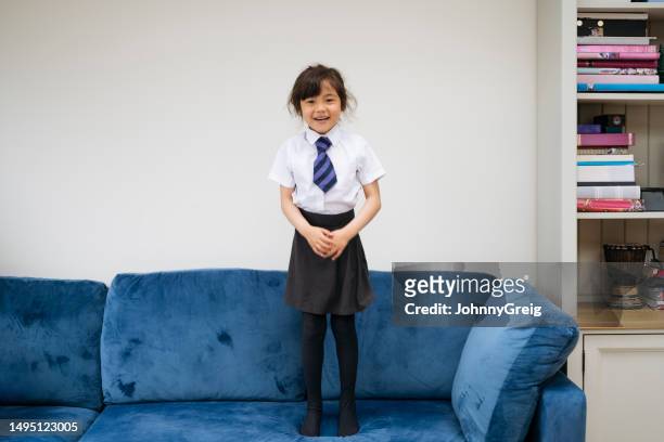 candid portrait of child standing on sofa in stocking feet - striped shirt stock pictures, royalty-free photos & images