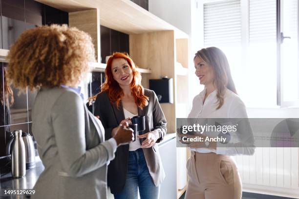 schöne frauen, die kaffee trinken und bei der arbeit reden - coffee break party stock-fotos und bilder