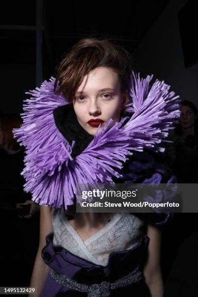 Backstage at the Sibling show during London Fashion Week Autumn/Winter 2016/17, a model wears a metallic white wrap top and a purple satin paper bag...