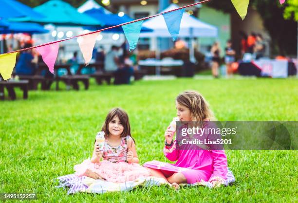 zwei niedliche glückliche verspielte kinder essen eis im freien auf einem karneval, jahrmarkt oder festival - schulfest stock-fotos und bilder
