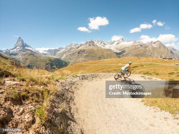 mountainbikerin auf feldweg, blick auf den berühmten matterhorngipfel in der ferne, schweiz - valais stock-fotos und bilder