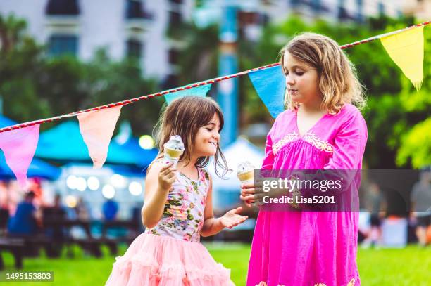 two cute happy playful kids eat ice cream outdoors at a carnival, fair or festival - gala stock pictures, royalty-free photos & images