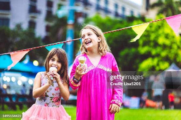 zwei niedliche glückliche verspielte kinder essen eis im freien auf einem karneval, jahrmarkt oder festival - schulfest stock-fotos und bilder