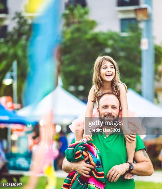 kinder reiten auf den schultern ihres vaters auf einem sommerkarnevalsfestival oder vergnügungspark im freien, familienspaß - schulfest stock-fotos und bilder