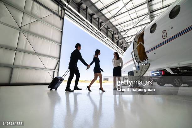 une hôtesse de l’air accueille un jeune couple à la mode à bord - business air travel photos et images de collection