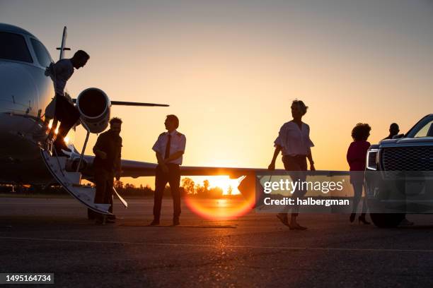 passagiere, die den privatjet in der abenddämmerung verlassen - airfield stock-fotos und bilder
