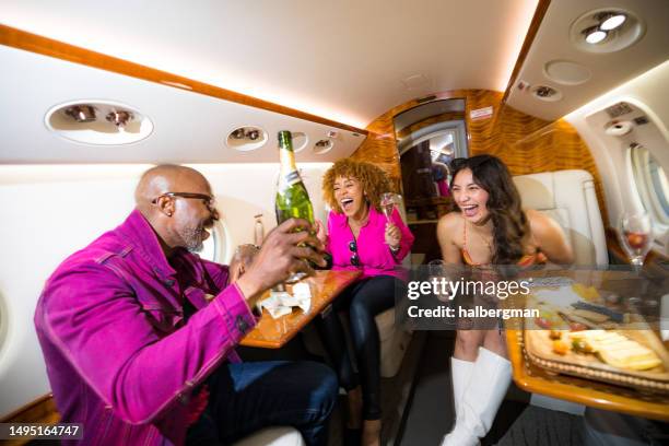 wealthy trio of passengers partying on private jet - party plane stock pictures, royalty-free photos & images
