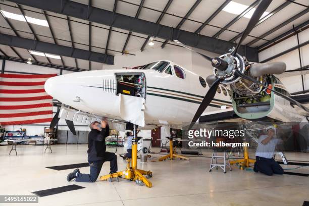 team of mechanics performing repairs on turboprop plane - aeroplane parts stock pictures, royalty-free photos & images