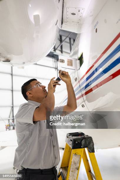 toma vertical del mecánico del avión revisando el lado del jet privado con linterna - aircraft mechanic fotografías e imágenes de stock
