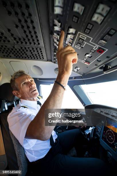 vertical shot of pilot pressing control buttons in cockpit of private jet - piloting stock pictures, royalty-free photos & images
