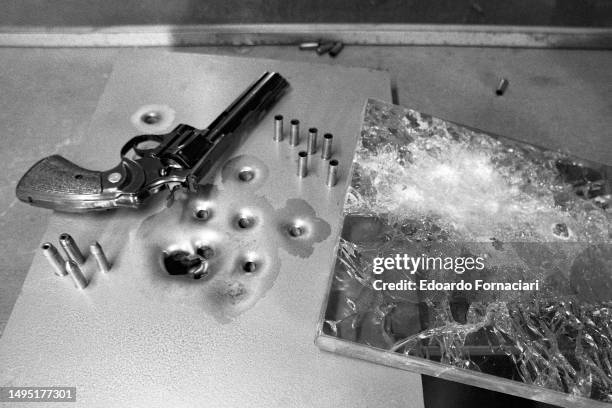 View of a handgun, several bullet casings, a sheet of pockmarked metal, and cracked glass at Fontanauto bodywork, Cuneo, Italy, March 25, 1978. The...