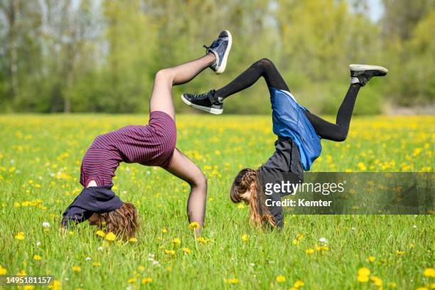 dos adolescentes haciendo una parada de manos al aire libre - girl in dress doing handstand fotografías e imágenes de stock