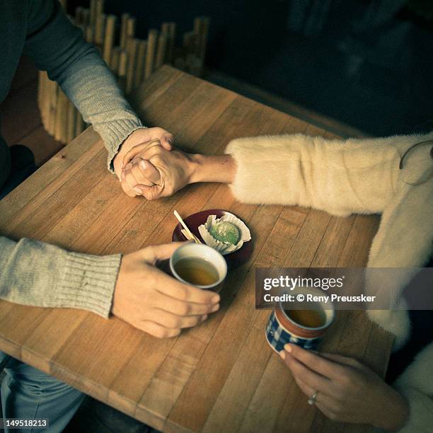 holding hands over tea - reny preussker foto e immagini stock