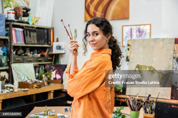retrato de una mujer adulta media sosteniendo un juego de pinceles en casa - pintor-artista fotografías e imágenes de stock