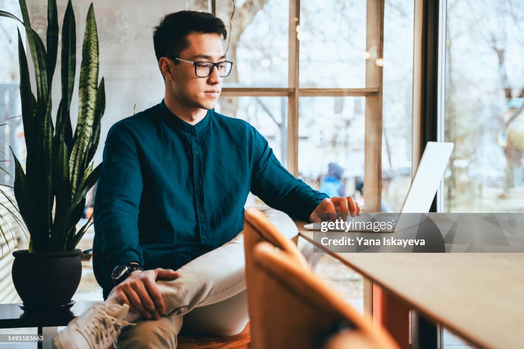 A progressive Asian businessman in modern casual clothing working in smart glasses