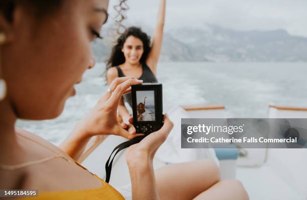 a woman takes a photo of a fellow passenger on a boat, using a digital camera - digitale camera stockfoto's en -beelden