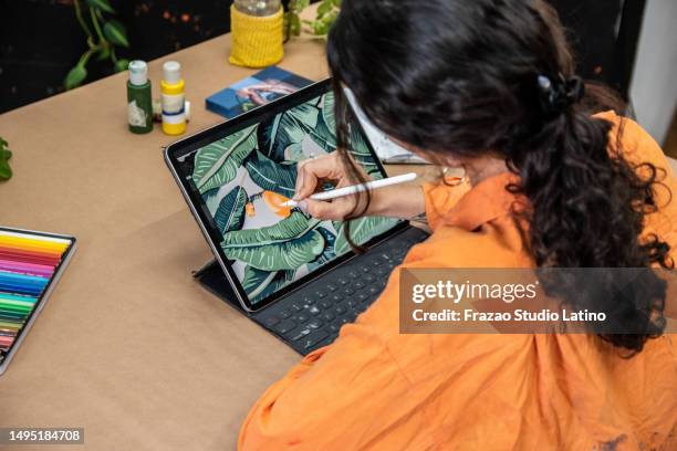 rear view of a woman painting/drawing with a digital tablet at home - digitized pen stock pictures, royalty-free photos & images