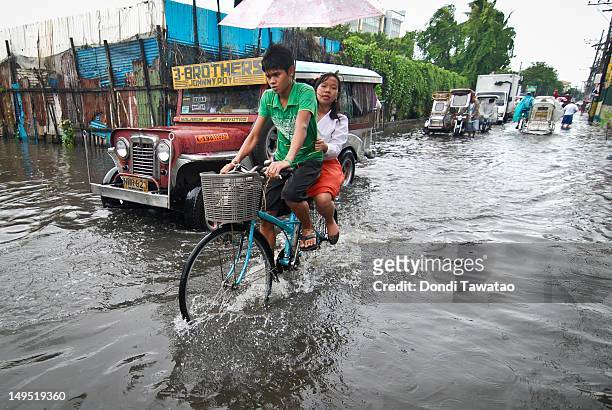 Residents pass through a flooded portion of the coastal town of Navotas on July 30, 2012 in Manila, Philippines. Heavy rains and strong winds brought...