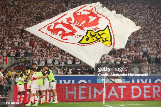 VfB Stuttgart fan waves a flag as Sehrou Guirassy of VfB Stuttgart celebrates with teammates after scoring the team's third goal during the...