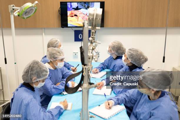 medizinstudent, der sich notizen macht, während er sich ein video zur durchführung einer autopsie ansieht - anatomy video stock-fotos und bilder
