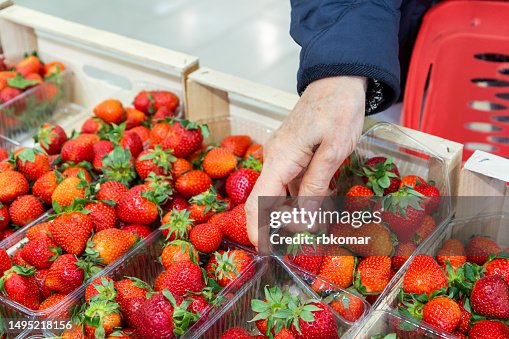 Strawberries in a container - choosing and buying farm berries and fruits in a supermarket Strawberries in a container - choosing and buying farm berries and fruits in a supermarket