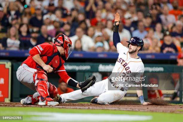Kyle Tucker of the Houston Astros beats the tag from Matt Thaiss of the Los Angeles Angels to score during the second inning at Minute Maid Park on...