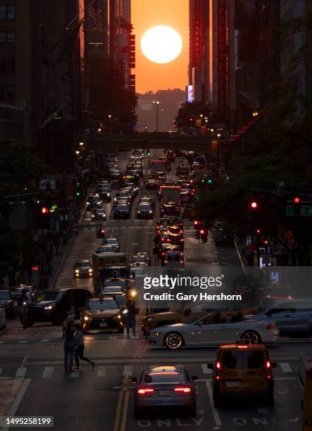 The sun sets over Weehawken, New Jersey as traffic moves along 42nd Street on June 1 in New York City.