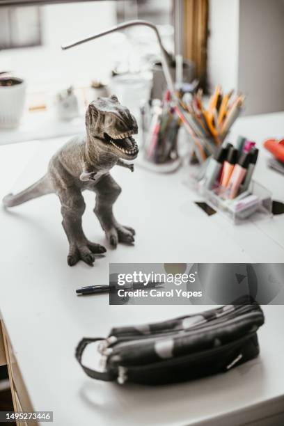 dinosaur toy rest on child desk a pencil case is beside - desk toy 個照片及圖片檔