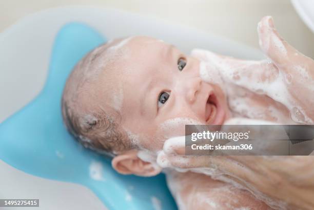 asian baby leaning back on the baby bathtub and enjoy after mother shower and scrub bath foam domestic life - baby shower gel stock pictures, royalty-free photos & images