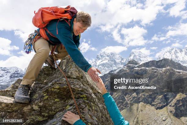 mountain guide offers helping hand from summit - coach hand bags stock pictures, royalty-free photos & images