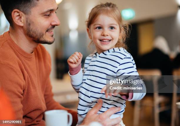 porträt eines glücklichen mannes, der sitzt und sein kleines mädchen auf dem schoß hält - strict parent stock-fotos und bilder