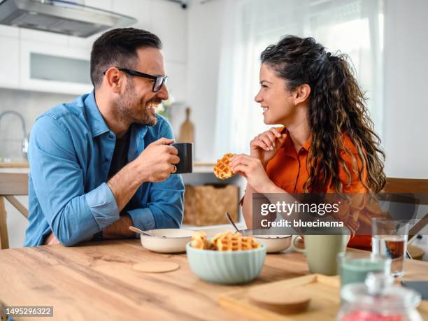 glückliches paar genießt gemeinsam das frühstück - 2 männer essen kekse stock-fotos und bilder