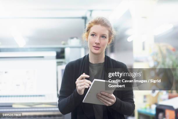 contemplative female worker preparing list at printing press - t shirt printing stock pictures, royalty-free photos & images