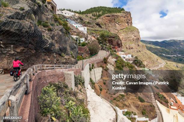 woman riding electric bicycle on mountain road - artenara fotografías e imágenes de stock