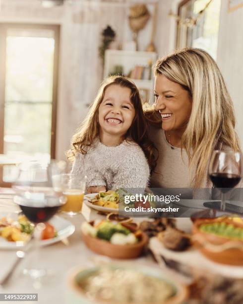 madre e hija felices disfrutando durante una comida en la mesa del comedor. - sentarse a comer fotografías e imágenes de stock
