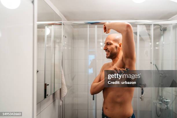 junger mann rasiert seine achselhöhle im badezimmer - behaart stock-fotos und bilder