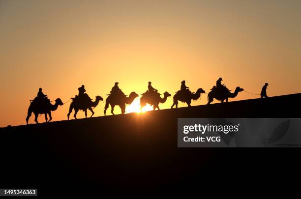 Tourists ride camels at the Mingsha Mountain and Crescent Spring scenic spot on June 1, 2023 in Dunhuang, Jiuquan City, Gansu Province of China.