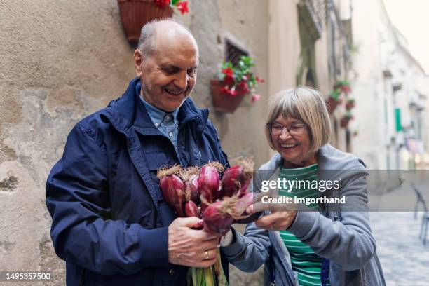 senior man giving a bouquet of onion to a senior woman in an italian town - allium flower imagens e fotografias de stock