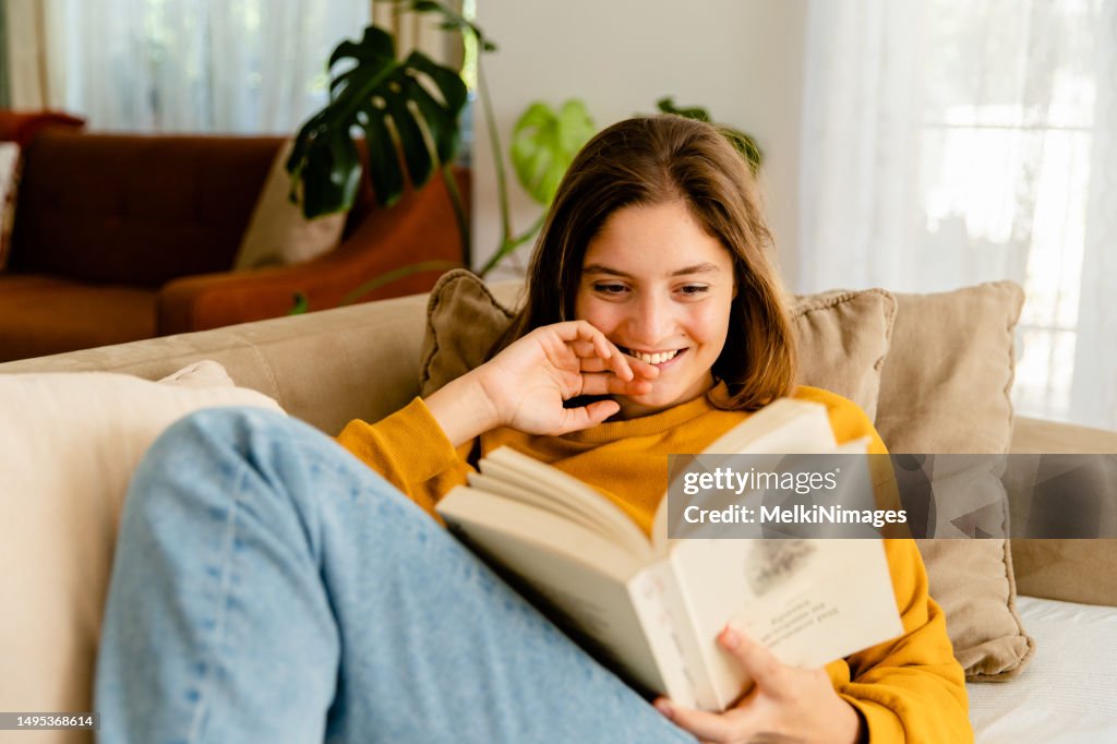 Woman relaxing on sofa at home and reading book
