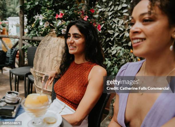 two woman in an outdoor cafe sit next to each other and smile - italian icecream stock pictures, royalty-free photos & images