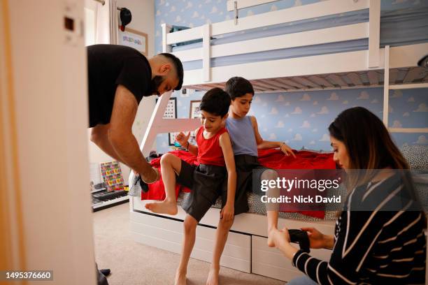 mum and dad helping their two children get dressed for school - female twins stock pictures, royalty-free photos & images