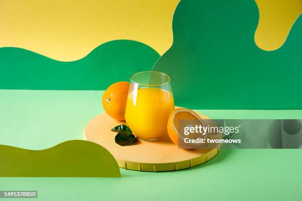 still life glass of orange juice and oranges on a colorful multi-colored background. - zumo de naranja fotografías e imágenes de stock