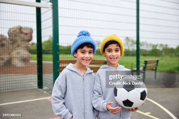 portrait of two young boys with their football - cute twins stockfoto's en -beelden